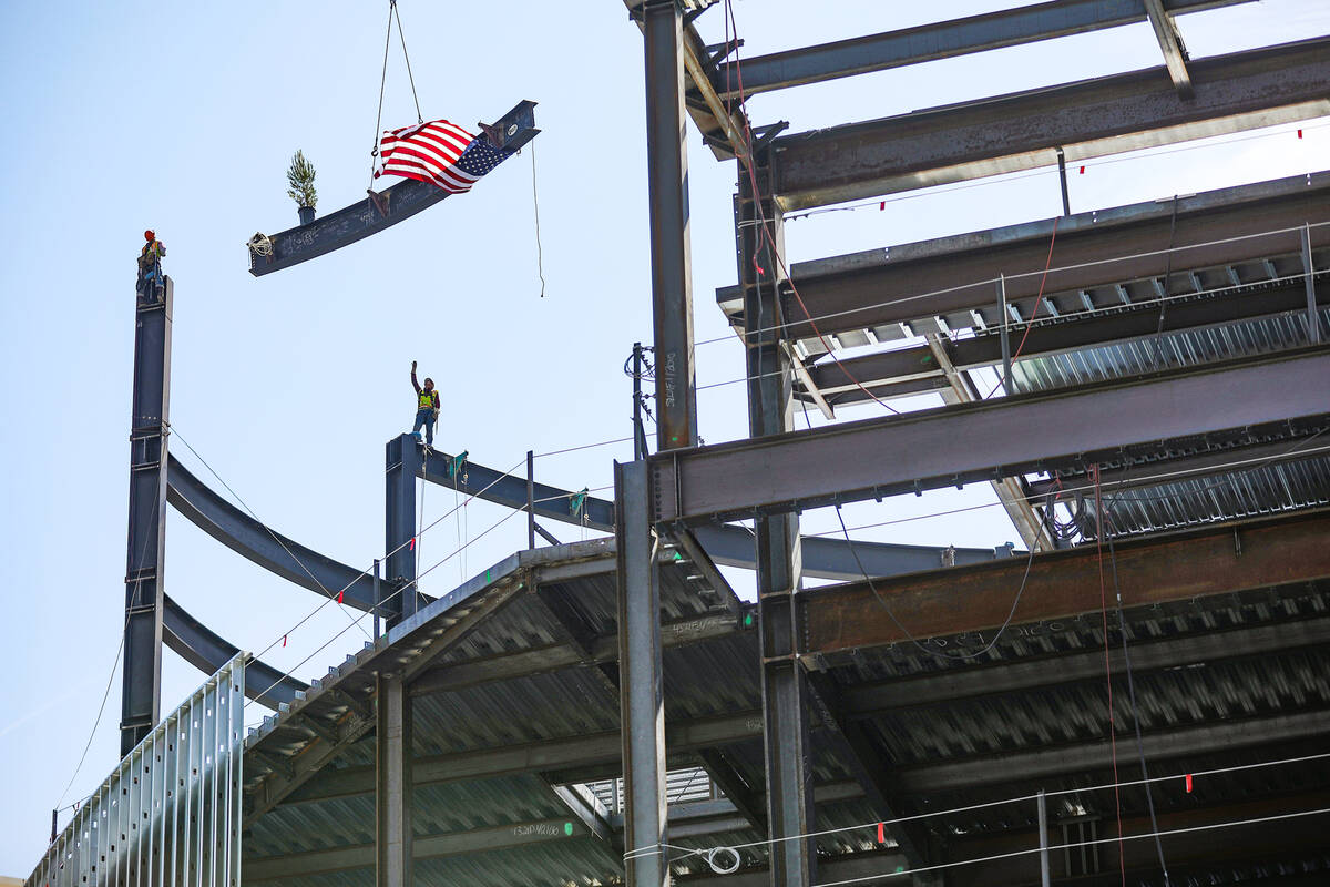 Workers secure the last beam into the building at the topping off ceremony for Project63, a new ...
