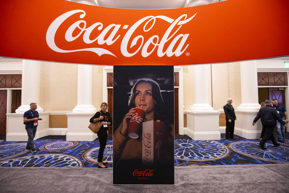 Attendees pass by a display for Coca-Cola at the CinemaCon trade show at Caesars Palace on Tues ...