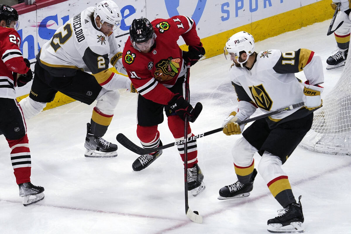 Chicago Blackhawks right wing Taylor Raddysh, center, controls the puck against Vegas Golden Kn ...