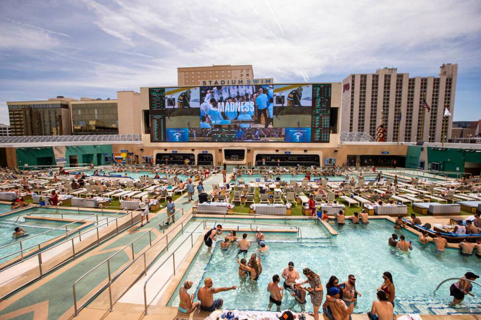 In this March 27, 2022, people watch as North Carolina takes on St Peter's in the Elite 8 round ...