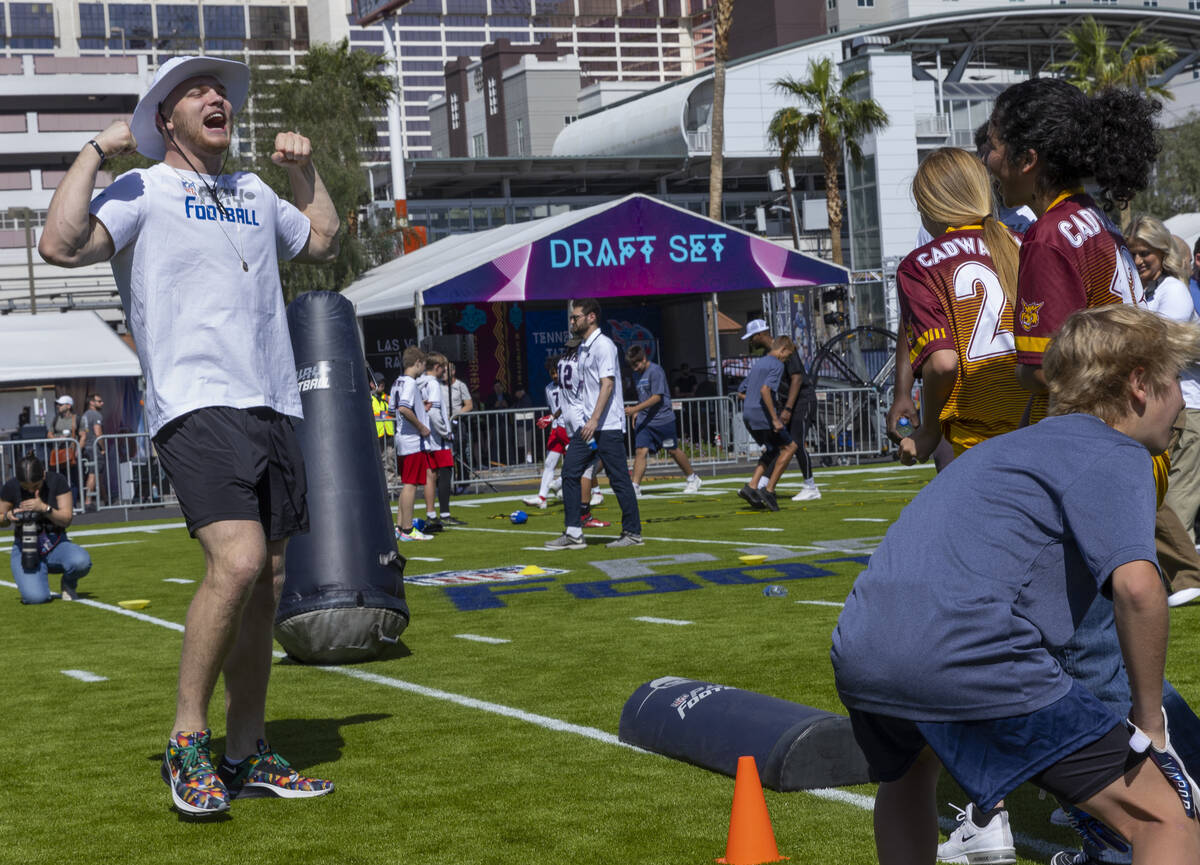 A 2022 NFL draft prospect Aidan Hutchinson of Michigan, left, shows a participant how to celebr ...