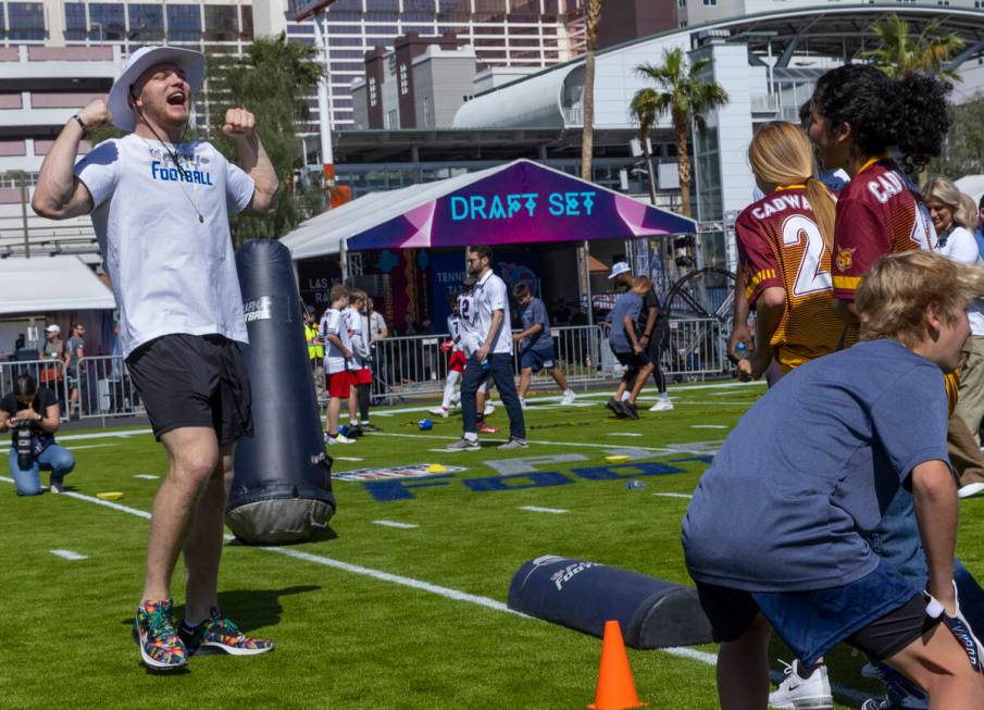 A 2022 NFL draft prospect Aidan Hutchinson of Michigan, left, shows a participant how to celebr ...