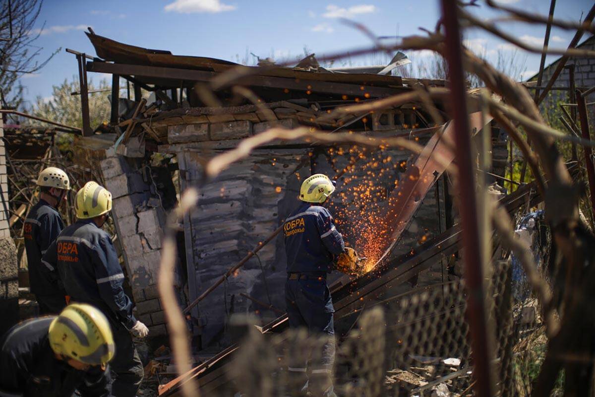 Ukrainian emergency service members remove debris from destroyed houses after a Russian rocket, ...