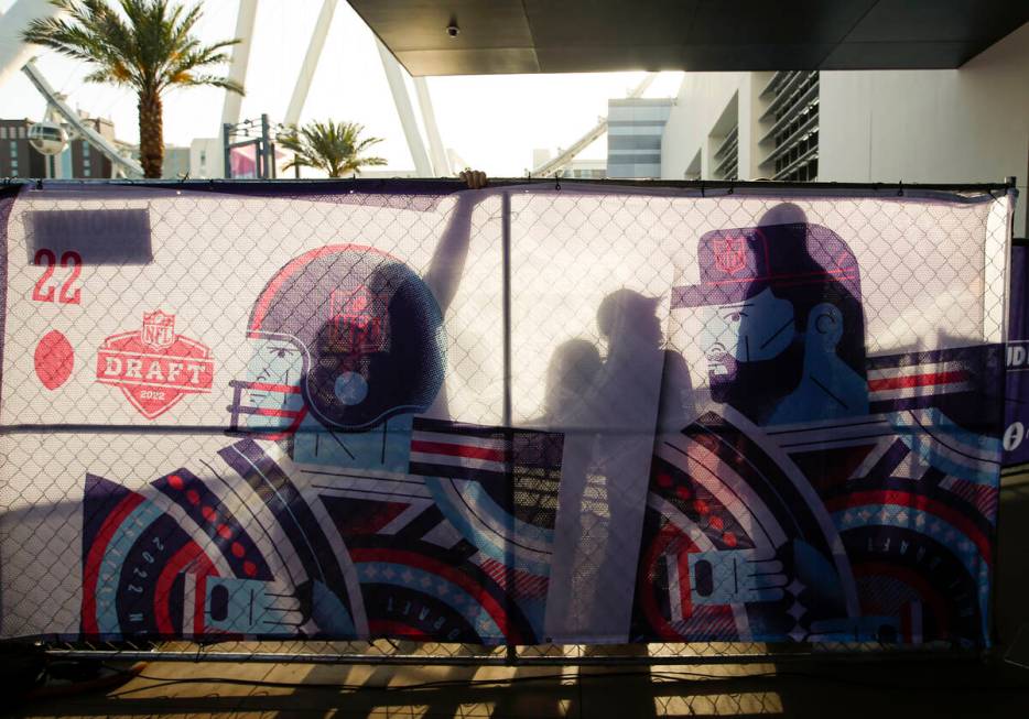 The shadows of fans are cast against the display during the first round of the NFL draft on Thu ...