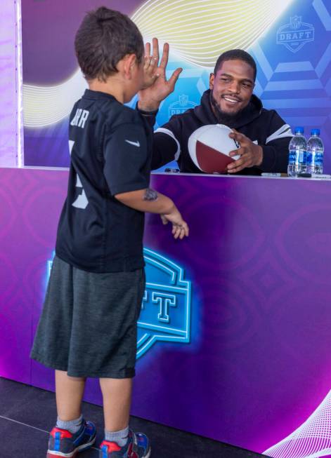Raiders’ Denzel Perryman, right, shares a high five with young fan Ramon Trejo, 5, of La ...