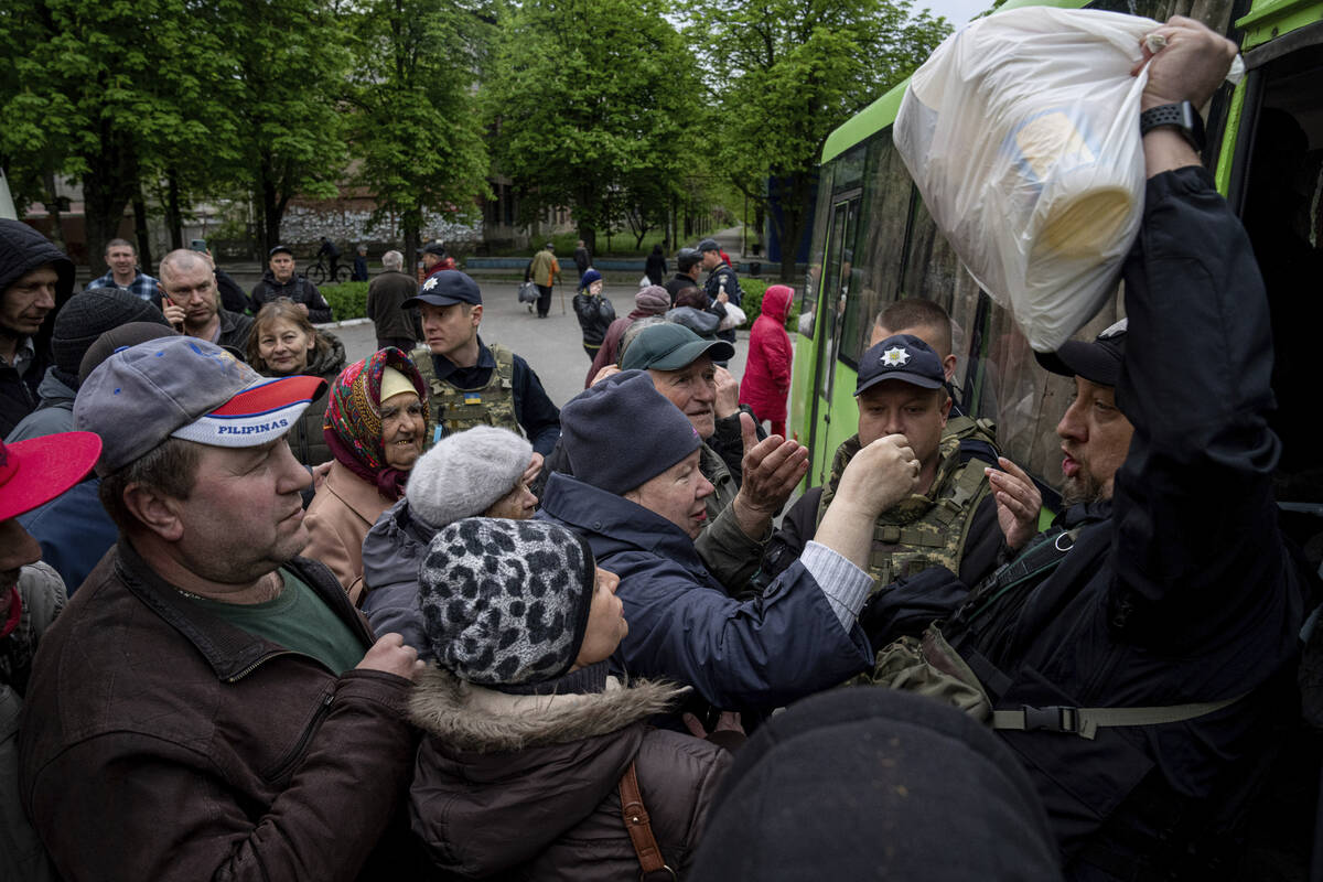 A Police officer, right, distributes humanitarian aid to local residents in Lyman, Donetsk regi ...