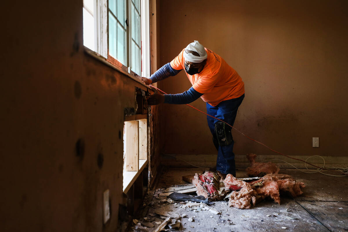 Juan Amador pulls out drywall and wall installation with signs of black mold in a room that Car ...