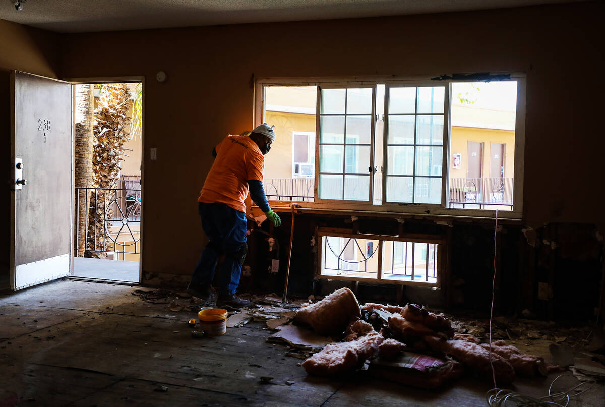 Juan Amador pulls out drywall and wall installation with signs of black mold in a room at the f ...