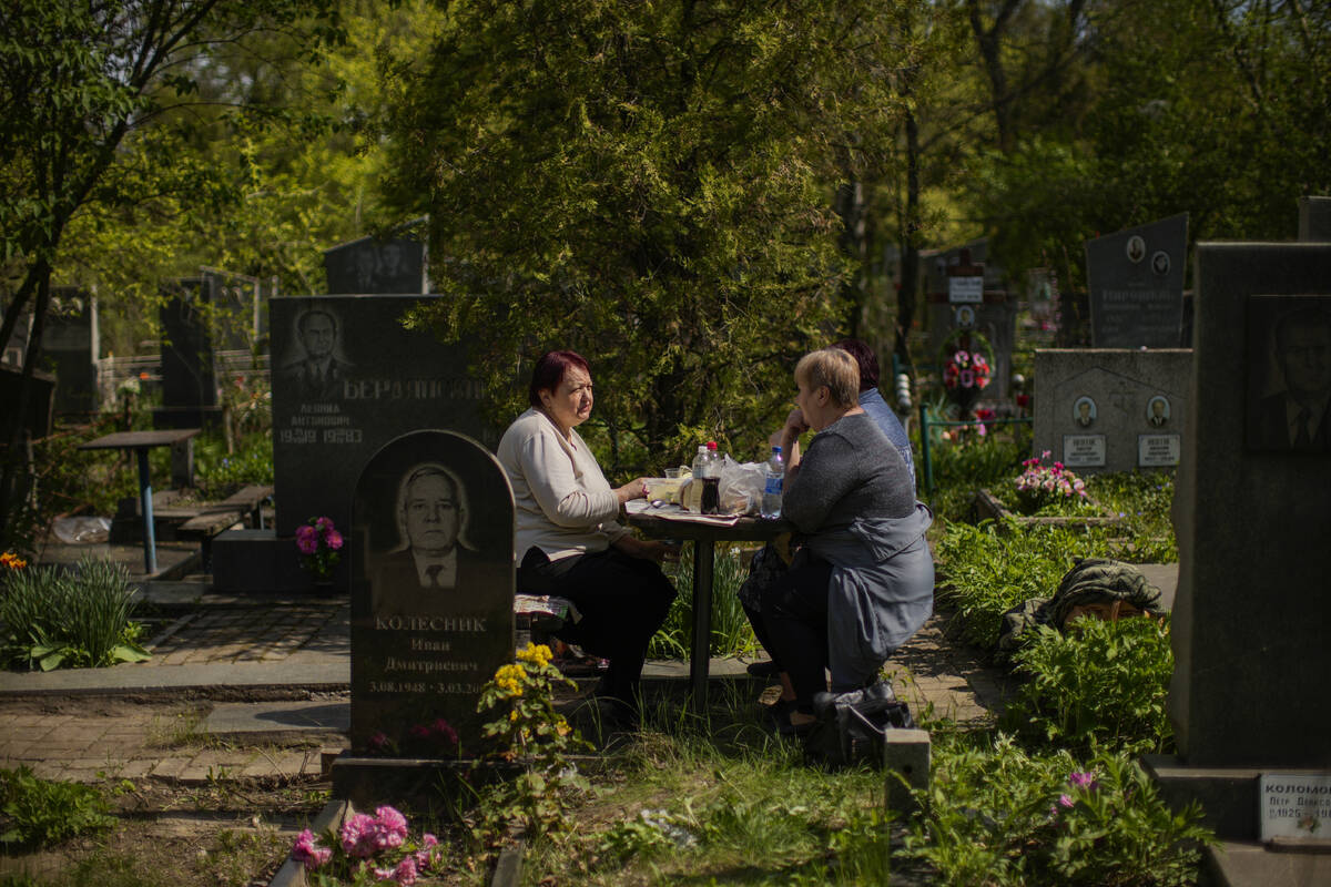 Vera Velakanova, left, and Lyudmila Vondarenko eat some food at the Kapustyanyy cemetery during ...