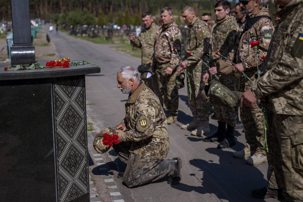 Irpin Territorial Defence and Ukrainian Army soldiers hold flowers to be placed on the graves o ...