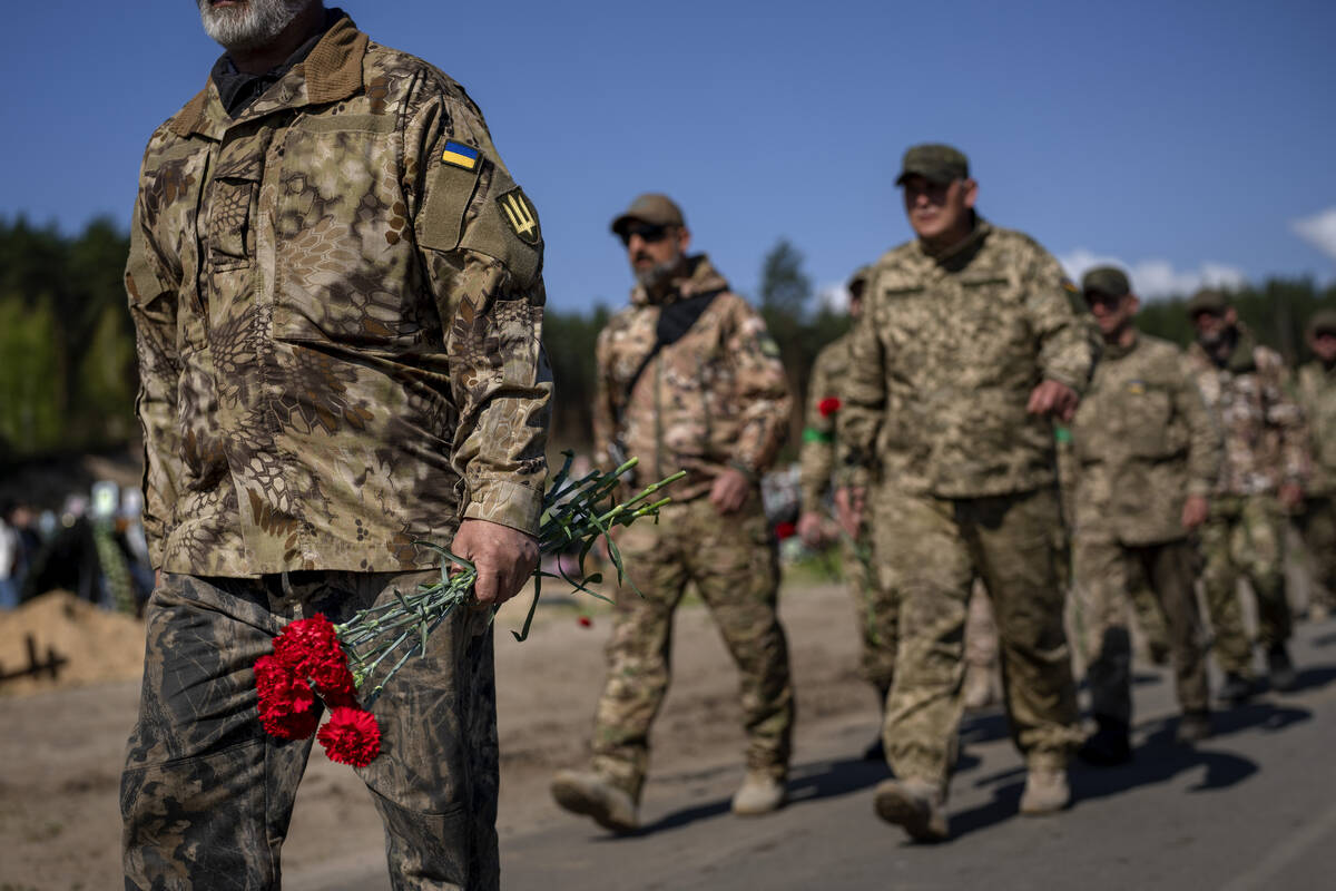 Irpin Territorial Defence and Ukrainian Army soldiers hold flowers to be placed on the graves o ...