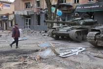 A woman walks past tanks of Donetsk People's Republic militia in Mariupol, in territory under t ...