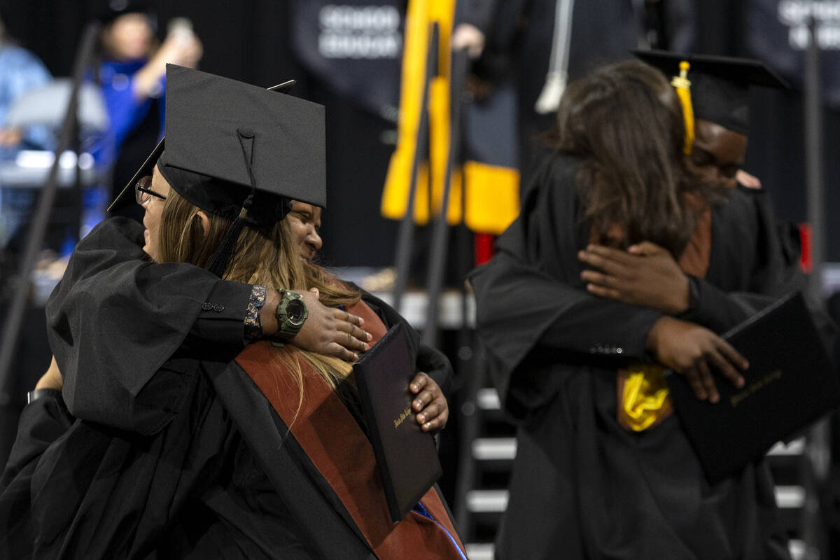 Graduates hug faculty members after walking across the stage during commencement for Nevada Sta ...