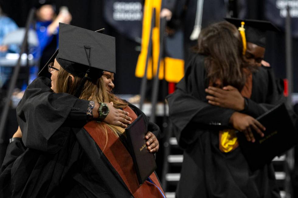 Graduates hug faculty members after walking across the stage during commencement for Nevada Sta ...