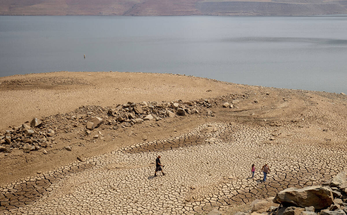 A family walks over cracked mud near Lake Oroville's shore as water levels remain low due to co ...