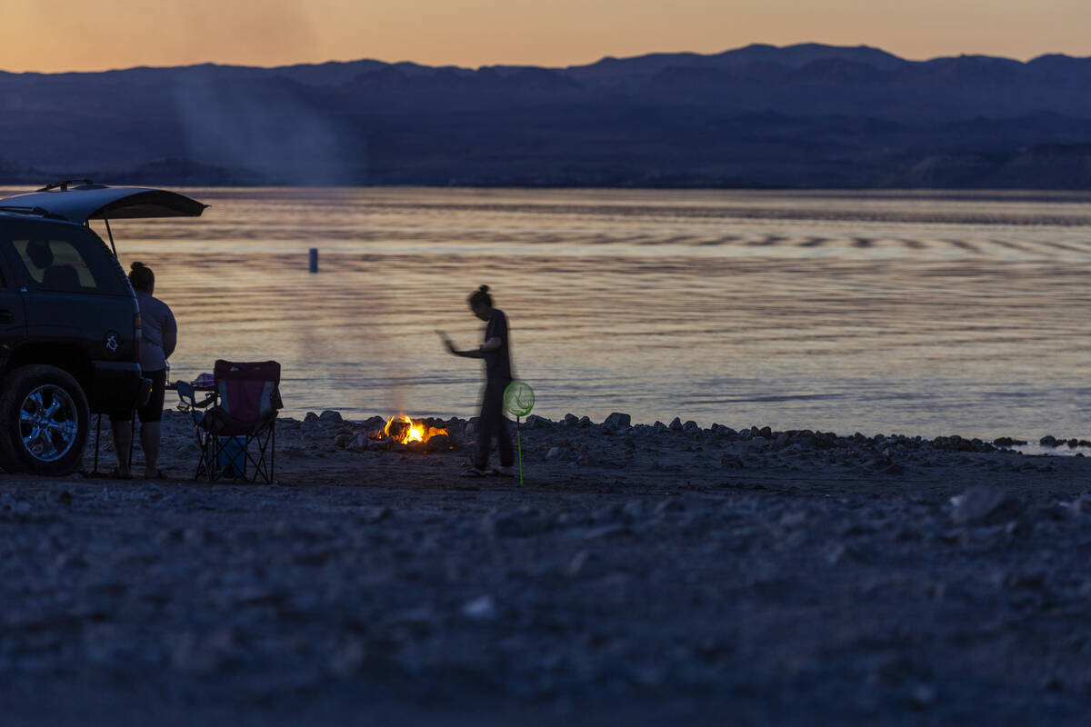 Visitors enjoy a fire on Boulder Beach at dusk as the waterline continues to recede along the s ...