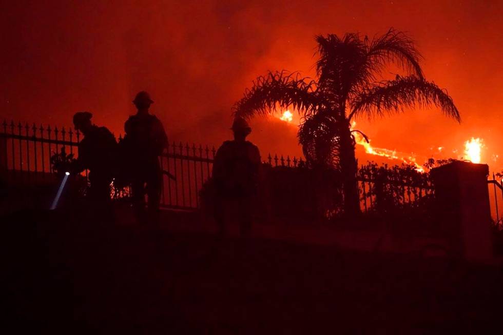 Firefighters work to put out a structure burning during a wildfire Wednesday, May 11, 2022, in ...