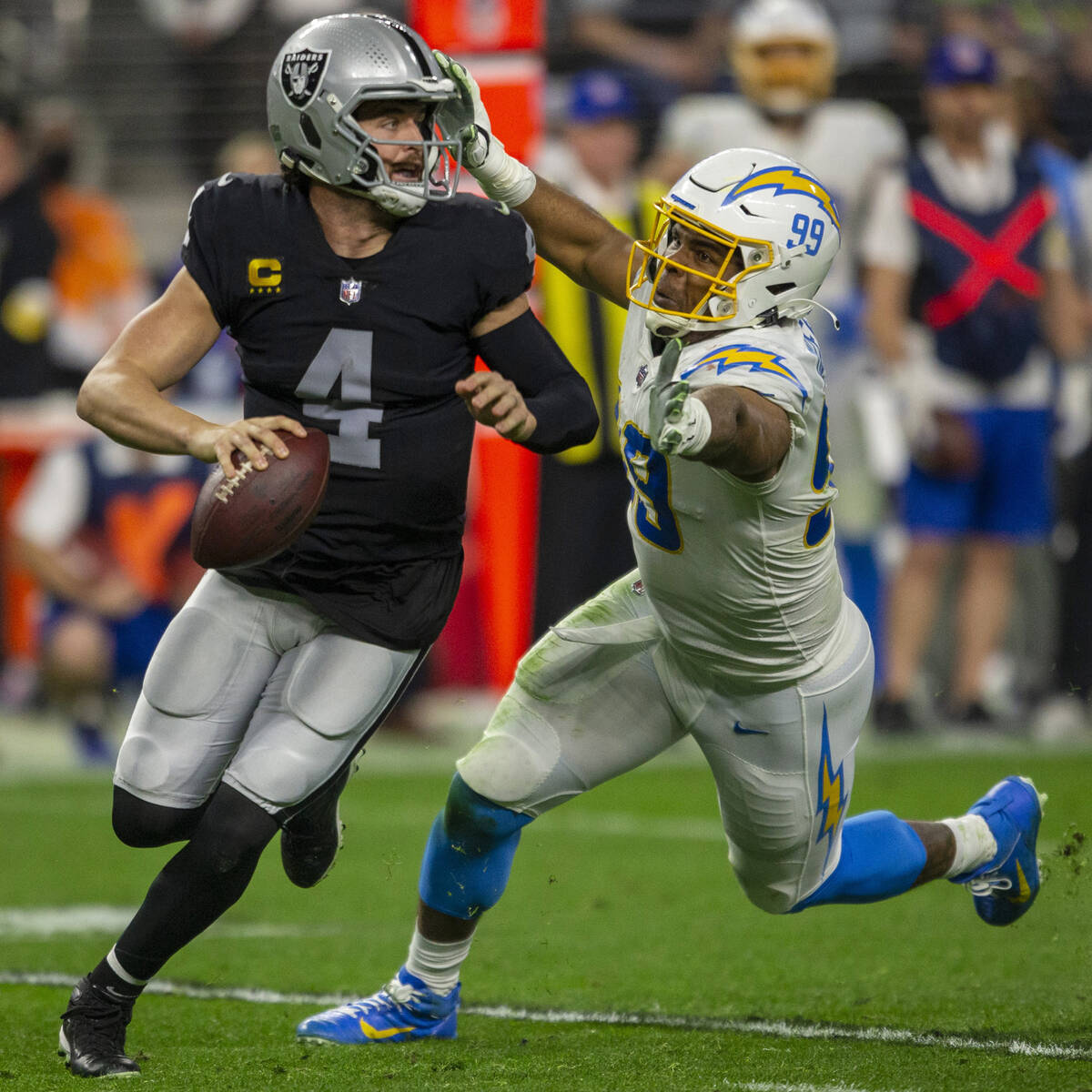 Raiders quarterback Derek Carr (4) scrambles to escape pressure from Los Angeles Chargers defen ...