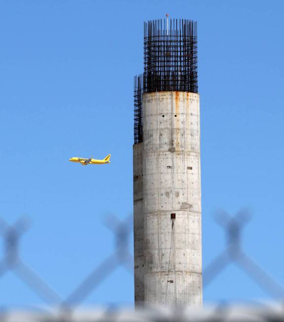 A airplane passes by two giant columns, parts of the partially built SkyVue observation-wheel p ...