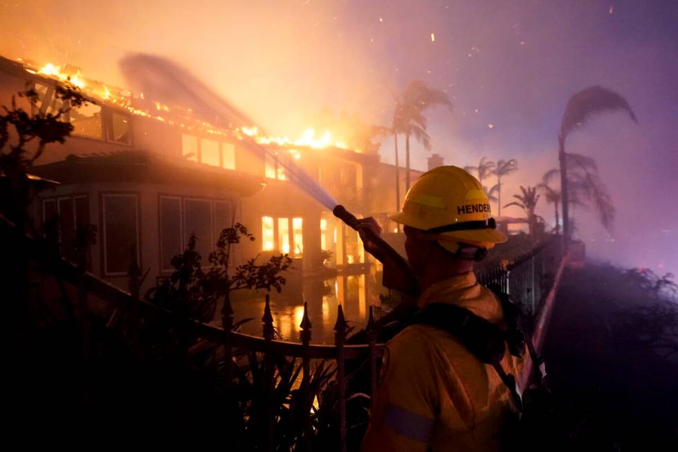 A firefighter works to put at a structure burning during a wildfire Wednesday, May 11, 2022, in ...