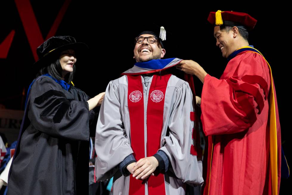 Postgraduate Jaime Carbajal Jr., center, is hooded by Dr. Federick Ngo, right, and UNLV Associa ...