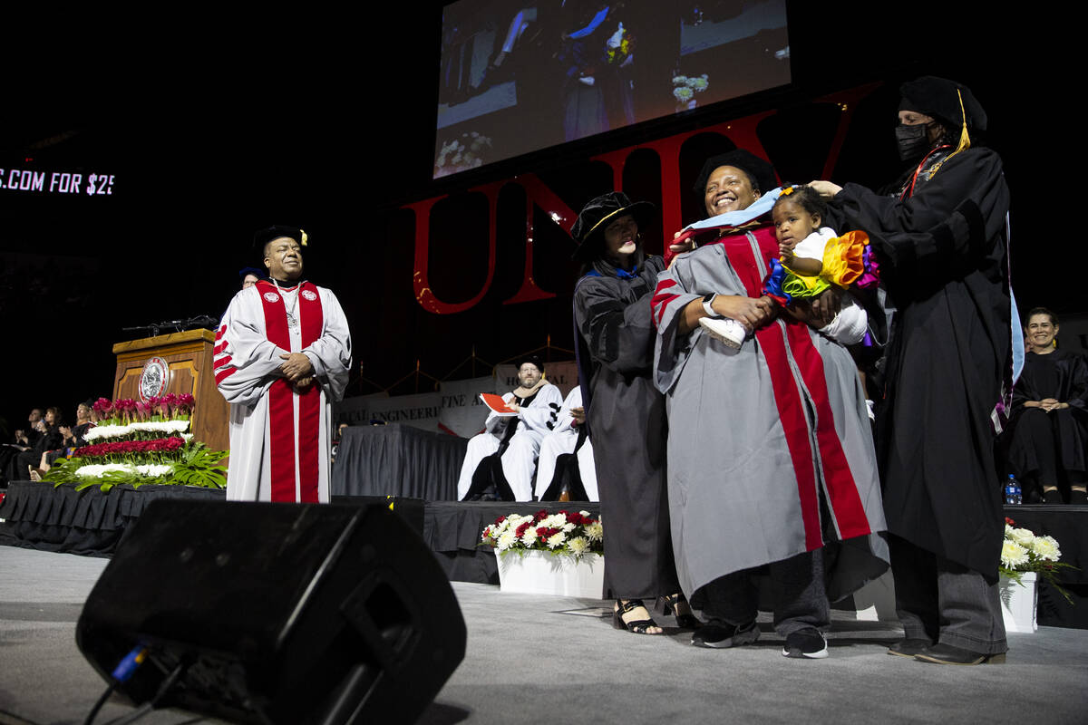 Postgraduate Ebony Sherman, second from right, with her 1-year-old daughter Makenzie, is hooded ...