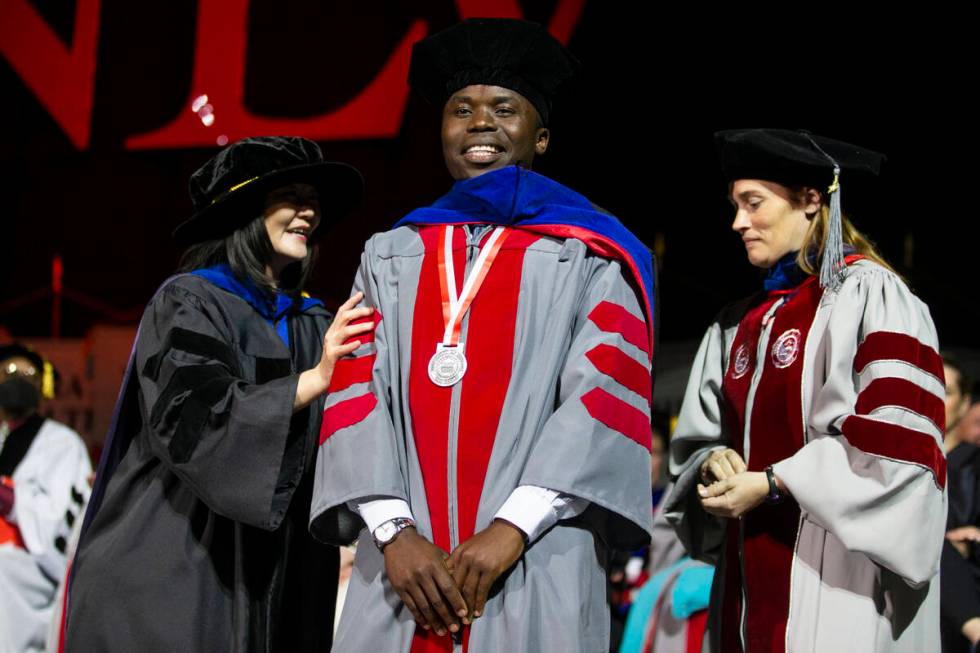 Postgraduate George William Kajjumba, center, is hooded by Dr. Erica Marti, right, and and UNLV ...