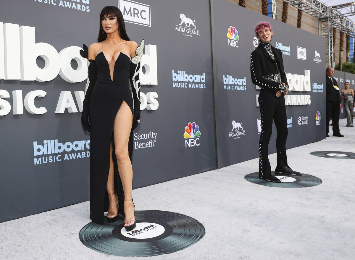 Megan Fox, left, poses as Machine Gun Kelly looks on from the red carpet for the Billboard Musi ...