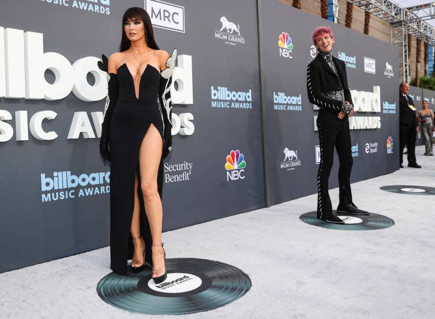 Megan Fox, left, poses as Machine Gun Kelly looks on from the red carpet for the Billboard Musi ...