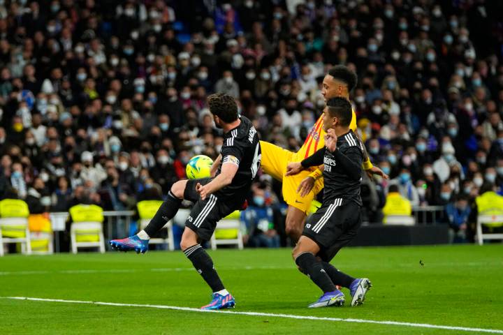 Barcelona's Pierre-Emerick Aubameyang, background, attempts a shot at goal in front of Real Mad ...