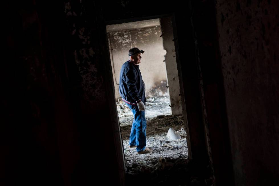 Serhii Klochko, 54, inspects his neighbour's apartment that was damaged during shelling in Khar ...