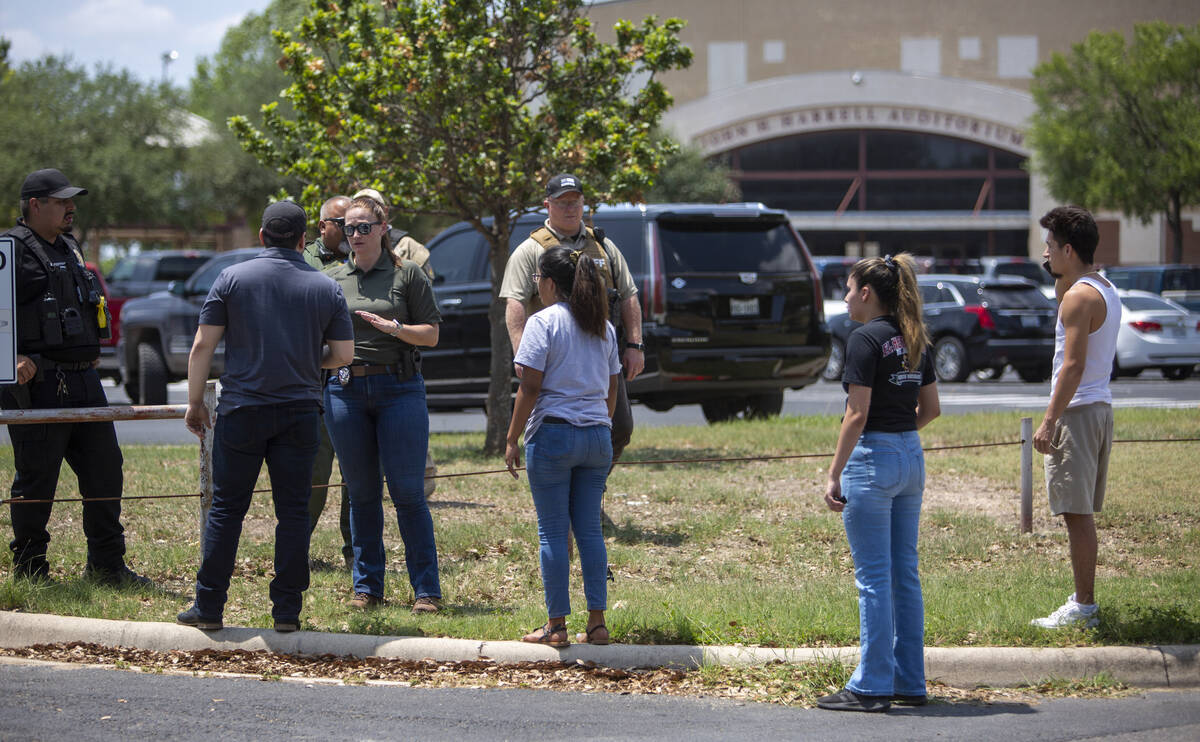 A law enforcement officer speaks with people outside Uvalde High School after shooting a was re ...