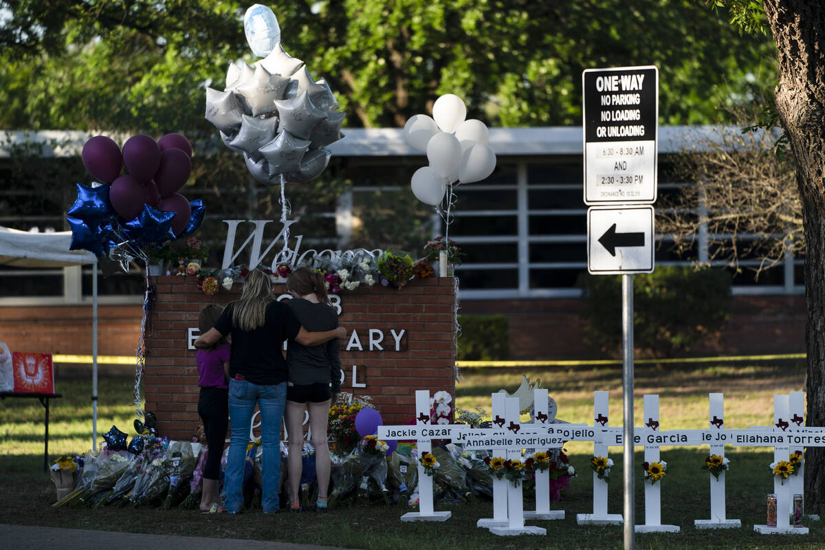 A family pays their respects next to crosses bearing the names of Tuesday's shooting victims at ...
