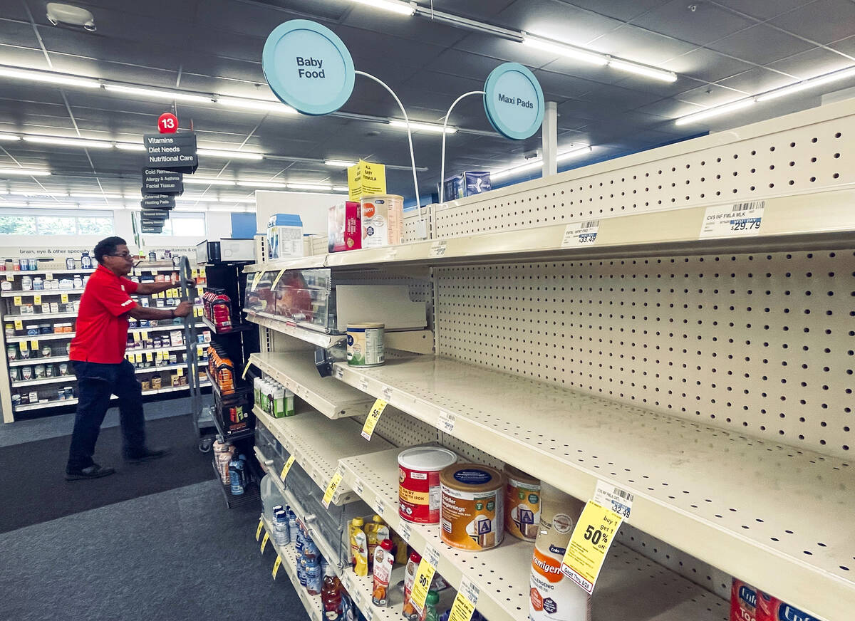 An employee walks near empty shelves where baby formula would normally be located at a CVS in N ...