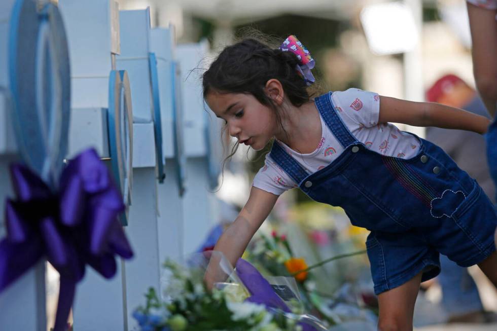 A child leaves flowers at a memorial site for the victims killed in this week's elementary scho ...