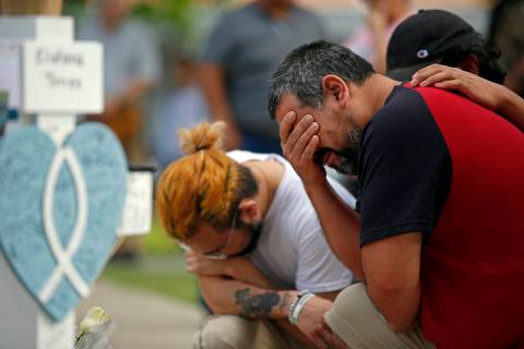Vincent Salazar, right, father of Layla Salazar, weeps while kneeling in front of a cross with ...