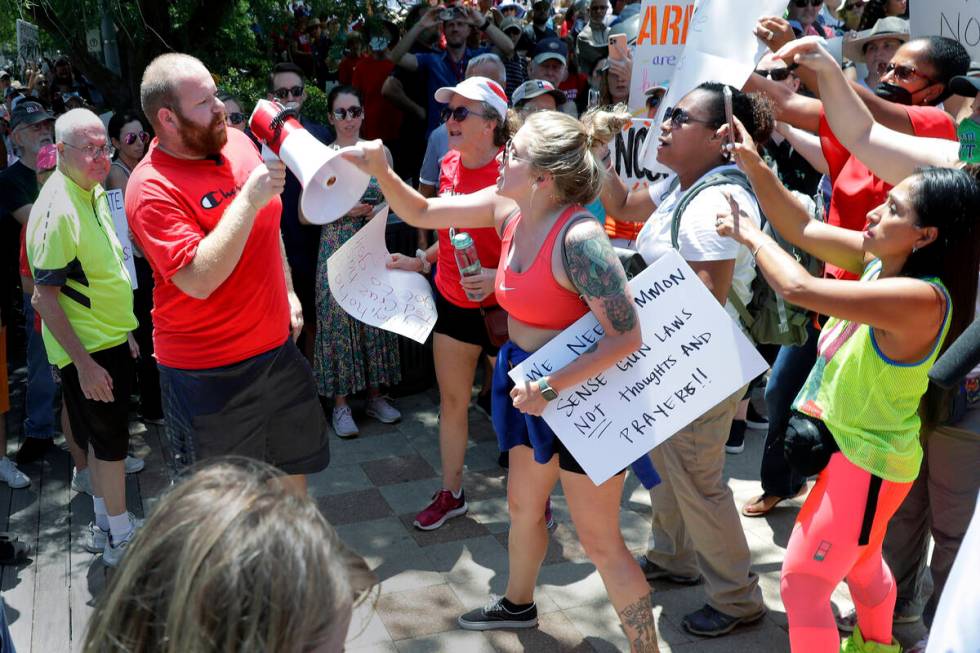 A counter-protester, left in red, is shouted down and has his megaphone taken away by rally att ...