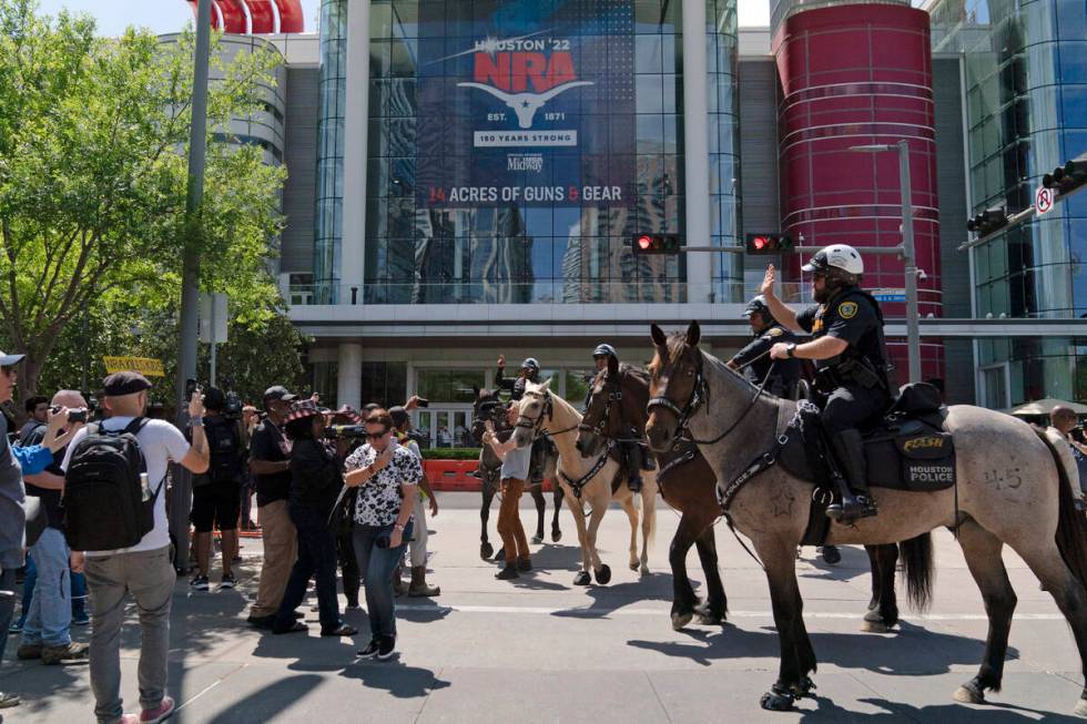 Mounted police officers tell protesters to move back across the street from the National Rifle ...