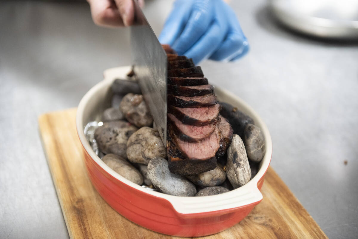 A member of the kitchen prepares the Chef's Special Short Rib Served on Ishiyaki Sizzling Stone ...