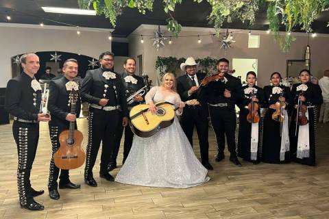 Newlyweds Mayra Ramos and Oscar Zuniga, in a white hat, pose with mariachis the day of their we ...