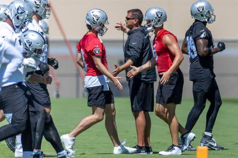Raiders quarterback Jarrett Stidham (3, left) greets teammate Derek Carr (4) while running a dr ...