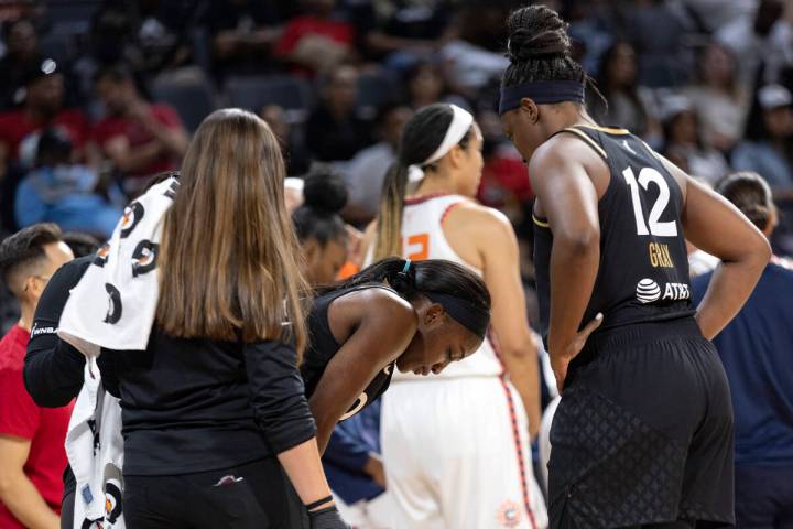 Las Vegas Aces guard Jackie Young, center, breathes through an injury before shooting her free ...