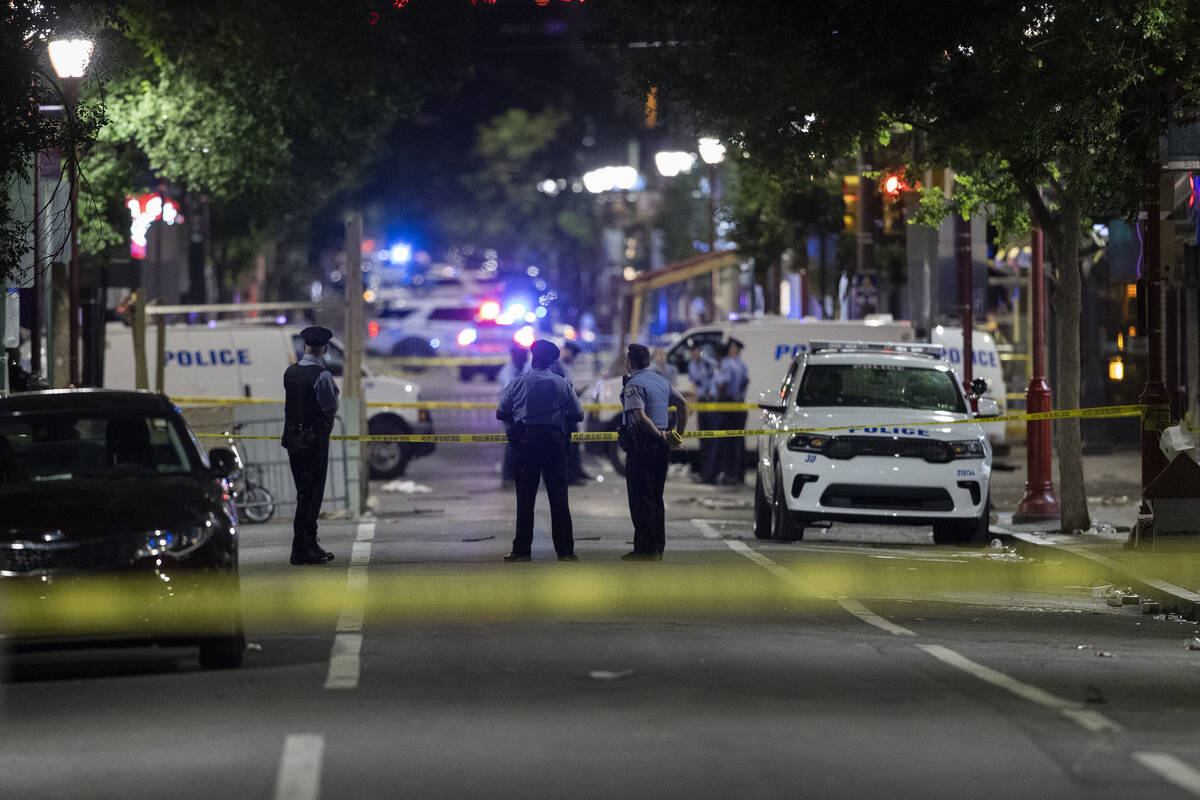 Philadelphia Police officers and detectives look over evidence at the scene of a shooting in Ph ...