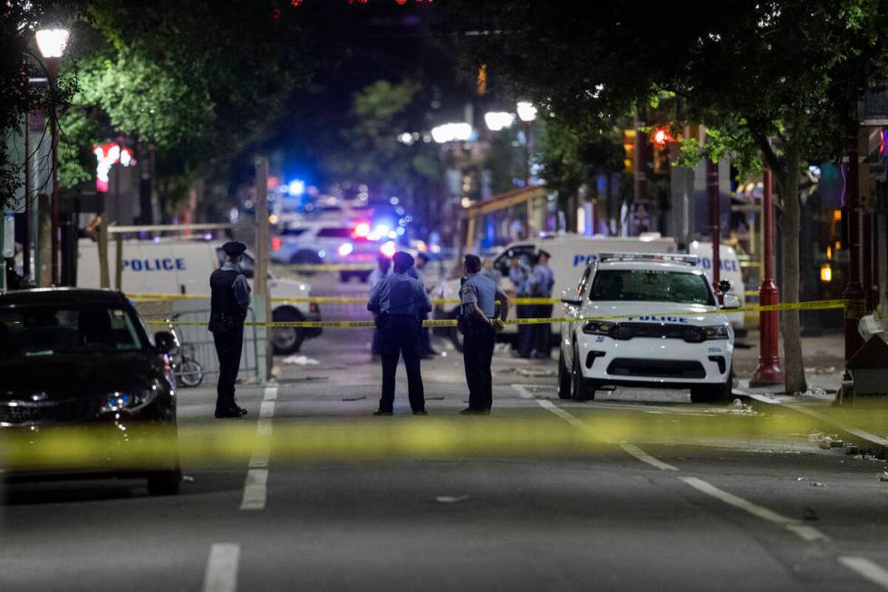 Philadelphia Police officers and detectives look over evidence at the scene of a shooting in Ph ...