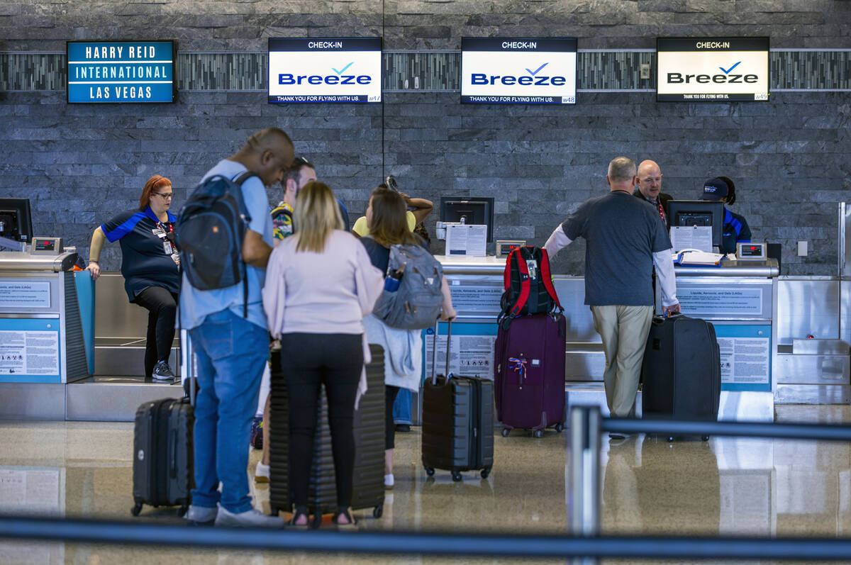 Breeze Airways passengers stand about the ticketing area checking in for a flights at Harry Rei ...