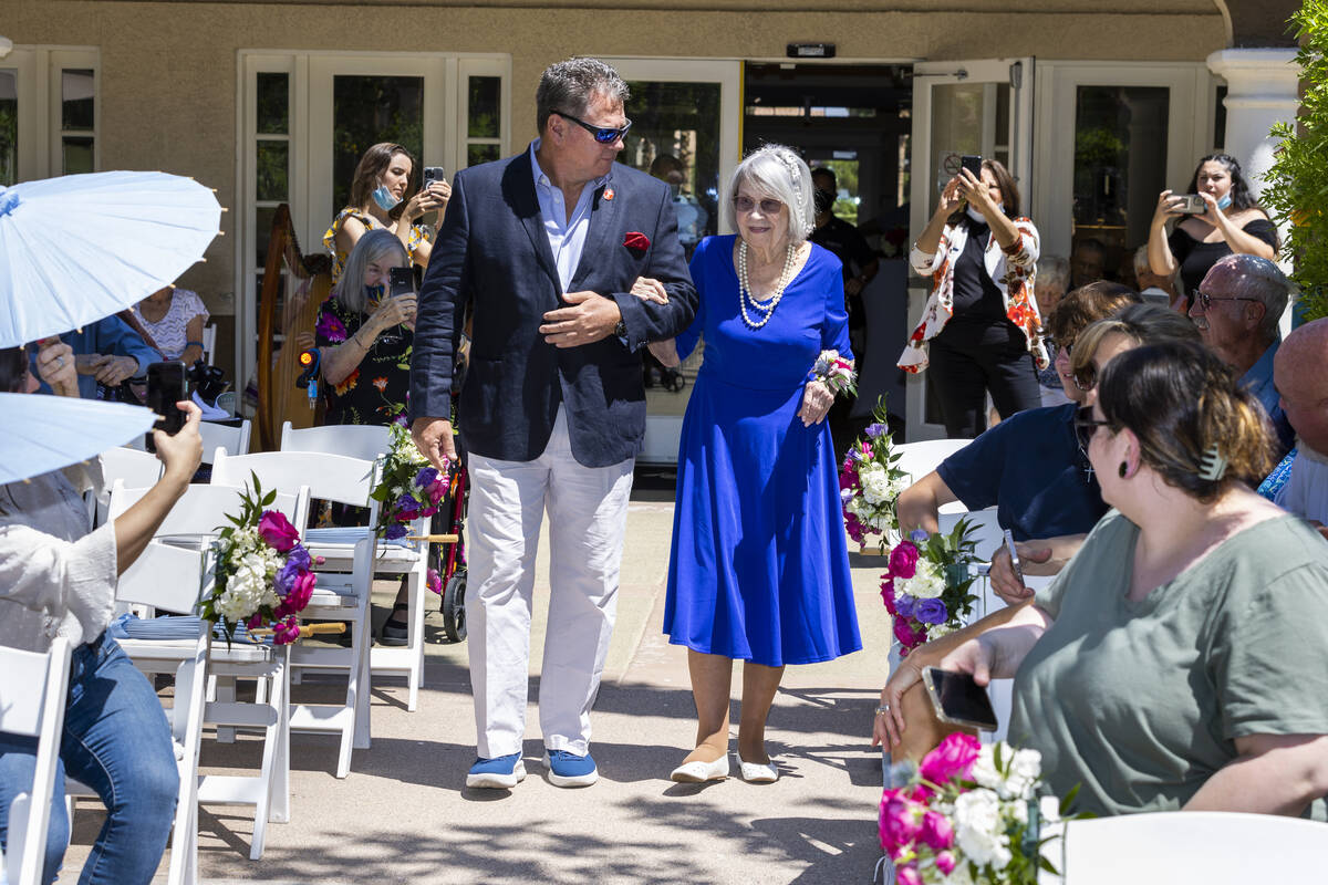 Bride Carolyn Brylinski, center, is escorted up the aisle by her son Mark Lewis-Jones as she re ...