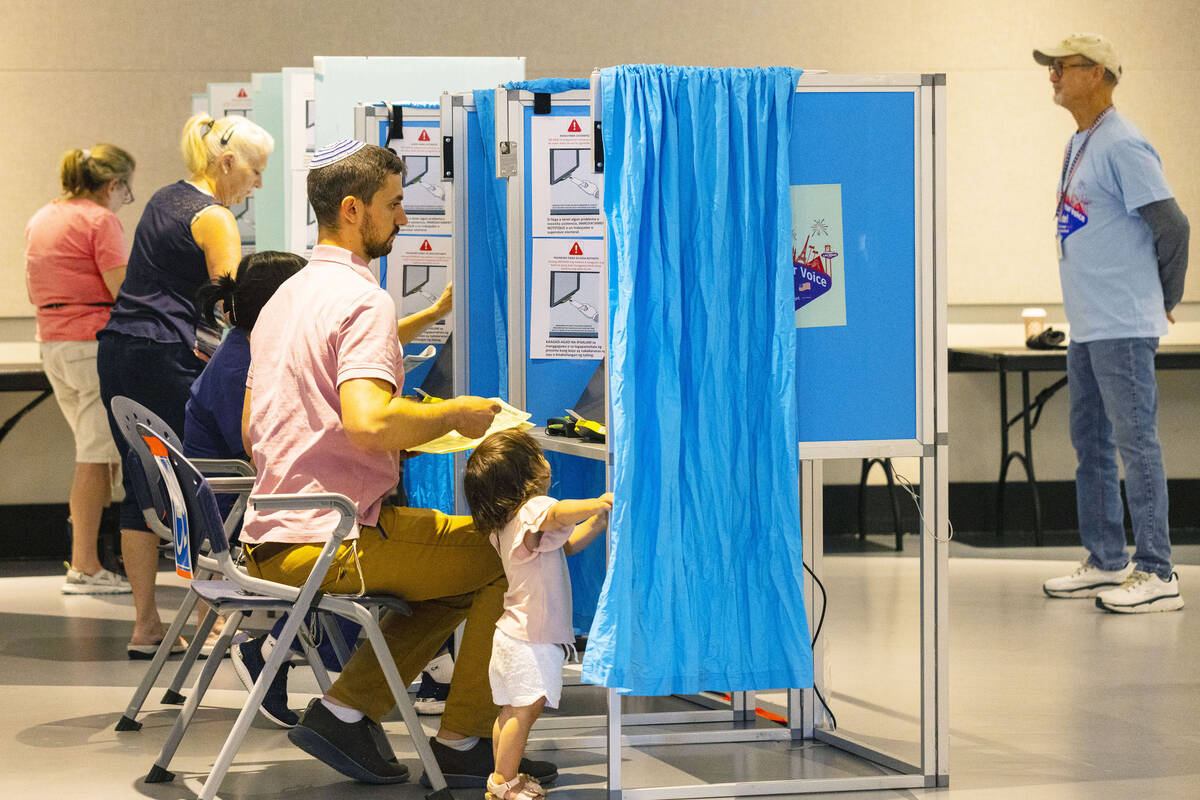 Voters, including Moshe Borvick, right, of Las Vegas cast their ballots as his one-and-a-half-y ...