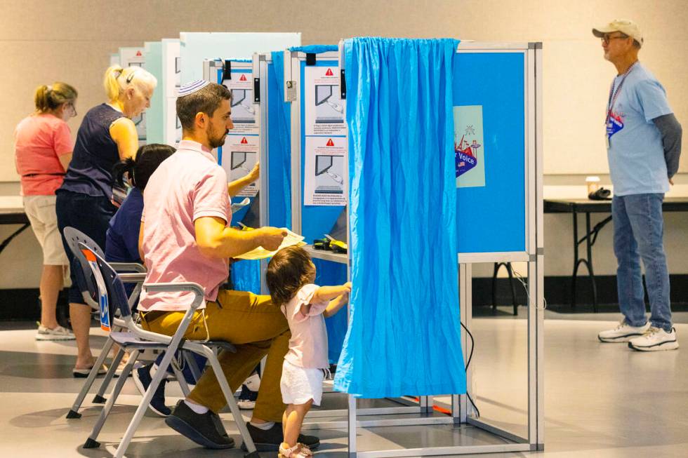 Voters, including Moshe Borvick, right, of Las Vegas cast their ballots as his one-and-a-half-y ...