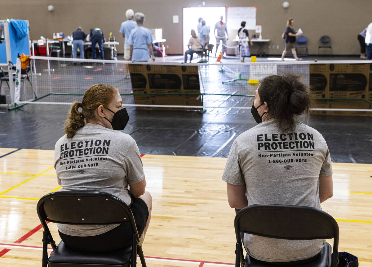 Election observers, who declined to give their names, watch as voters cast their ballots at a p ...