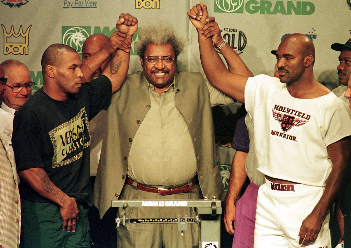 Boxing promoter Don King raises the arms of MIke Tyson and WBA Heavyweight Champion Evander Hol ...